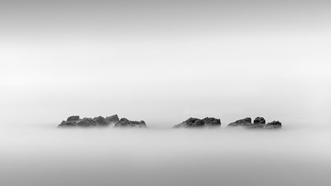 Jagged rocky islands emerging through mist