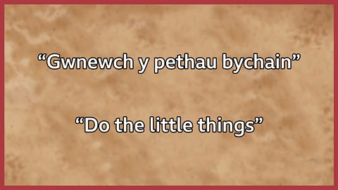 The quote "do the little things" in Welsh and English.