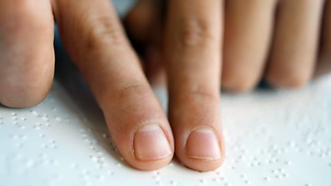 A school-age student reading Braille with their fingertips