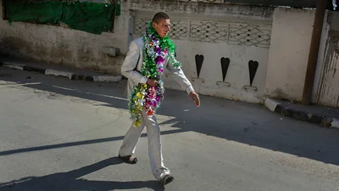 Tanya Habjouqa/NOOR West Bank, 20 April 2014: A man walks through a village wrapped in celebratory tinsel (Credit: Tanya Habjouqa/NOOR)