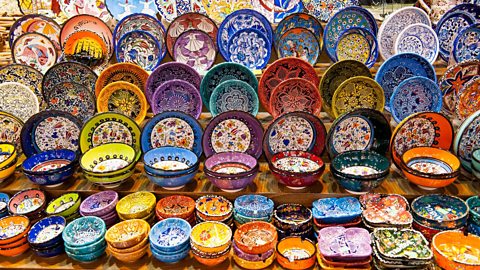 Many colourful dishes are on display on wooden shelves