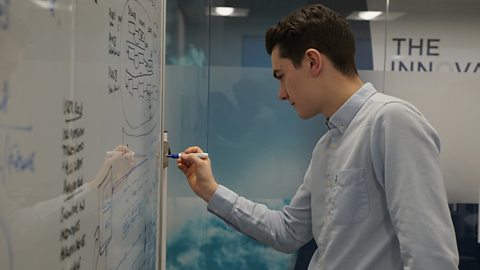 Ben writing ideas on a whiteboard.