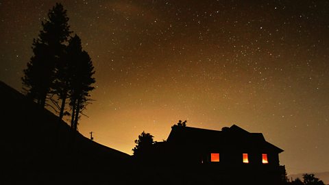 At night a light is visible in the upstairs window of a house.