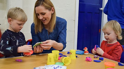 A brother and sister and their mum playing with play dough.