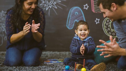 A man and a woman clapping along with their toddler son in playgroup.