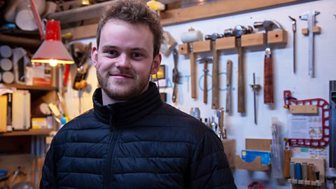 Miles in his workshop, smiling at the camera. 