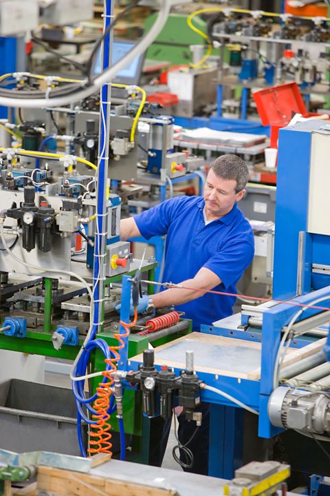 Worker operating machinery on production line in factory