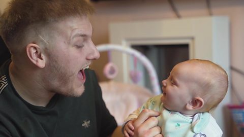 Dad smiling and looking at his little baby who is looking back at him