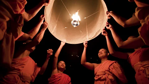 Getty Buddhist monks launch a sky lantern during the Yee Peng Festival in Chiang Mai. The ritual symbolises the release of kindness and goodwill (Credit: Getty)