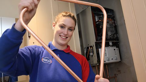 Sophie holding some copper pipe.