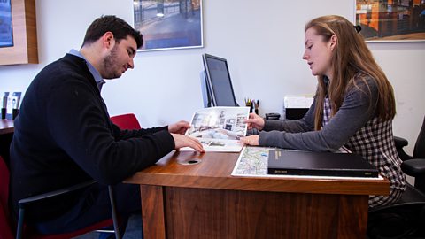 Samantha showing a property brochure to a client.