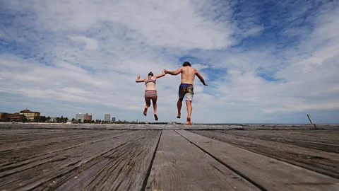 Getty Father and daughter jump off the pier at South Melbourne Beach (Credit: Getty)