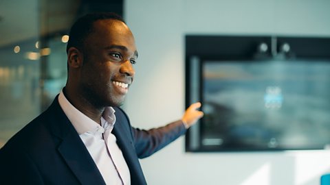 Hassan pointing at a screen in a meeting.