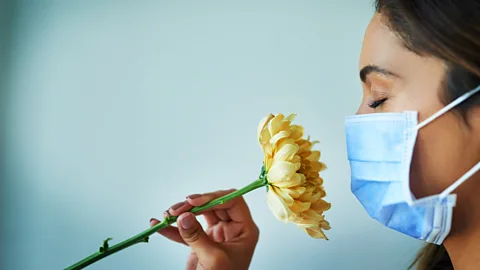 Getty Images Woman in mask snigging flower (Credit: Getty Images)