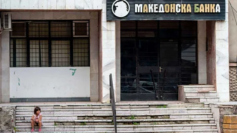 Getty Images A young girl sits outside a bank in Veles (Credit: Getty Images)