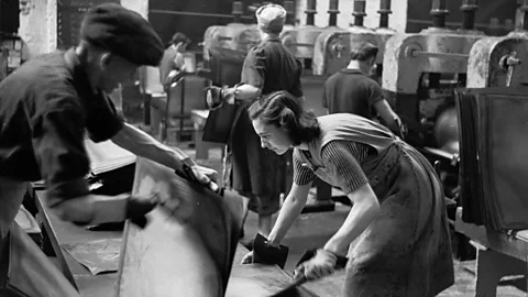 Getty Images Even in Welsh factories in the 1950s, some women wore colourful blouses under their work aprons (Credit: Getty Images)