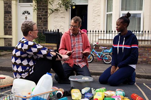 Hugh sits with the Bristol residents in their street, surrounded by single-use plastic items.