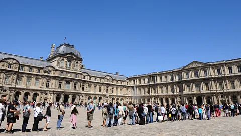 Getty Images Tourists queue in front of the Louvre in Paris in 2017. The museum shut down for one day earlier this year after employees walked out due to overcrowding (Credit: Getty Images)