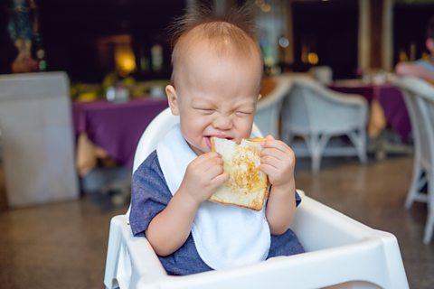A baby eating in a high chair.