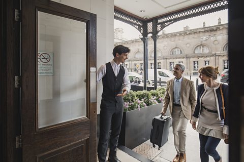 A doorman welcoming guests to a hotel.