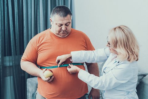 An obese man having his waist measured.