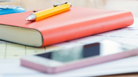 A notepad and pen next to a mobile phone