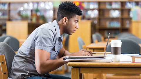 Boy studying on laptop in library