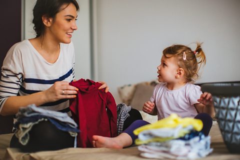 Mother folding laundry with child