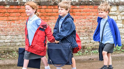 Three children walking on a road.