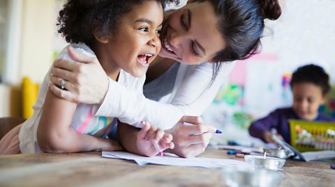 A mother and daughter laughing and drawing.