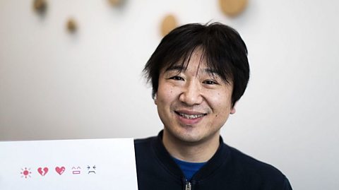 Shigetaka Kurita holding some emoji drawings