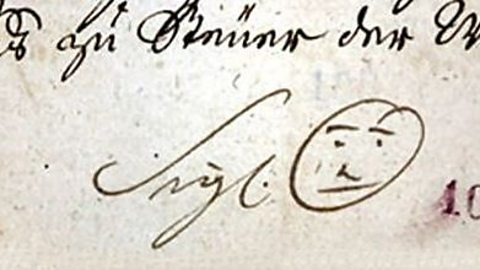 Signature with a face drawn next to it.