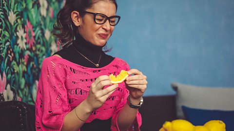 A woman pulling a face after sucking on a lemon.