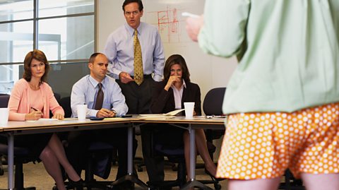 Man giving presentation in underwear in front of baffled colleagues.