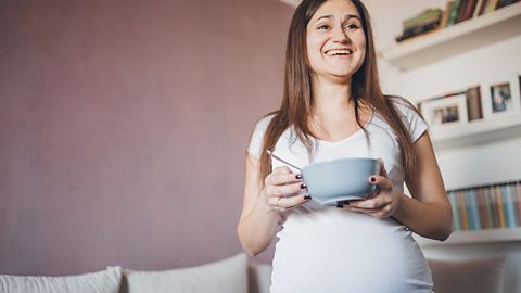 Pregnant woman eating out of a bowl