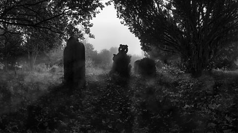 Three graves silhouetted in a misty graveyard