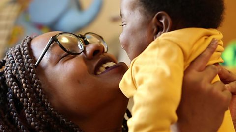 Woman holding up her baby close to her face and smiling