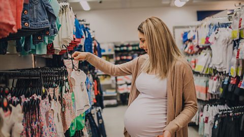 Pregnant woman shopping in a supermarket for baby clothes