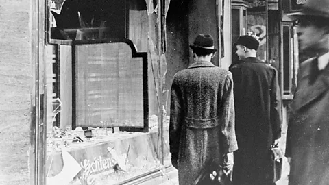 Getty Images Germans pass by the broken windows of a shop in the aftermath of Kristallnacht, a night which showed the world how dangerous Germany was becoming for Jews (Credit: Getty Images)