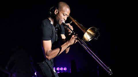 Trombone Shorty playing his trombone on stage.