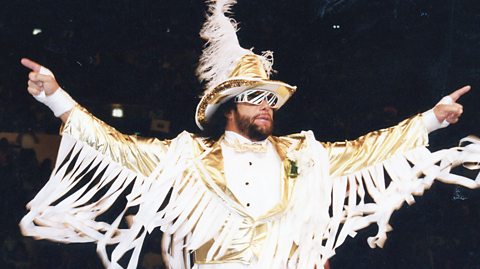 Macho Man Randy Savage dressed in white and gold suite and cavalier hat.