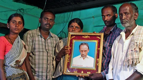 Getty Images Gopamma Nayaka holds the portrait of her husband Hanamuantha, accompanied by her two sons, daughter and uncle (Credit: Rachel Nuwer)