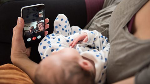 Woman holding baby and making video call on her phone