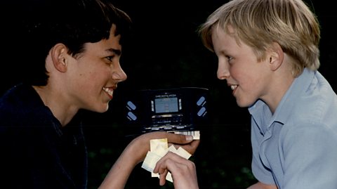 Two children holding the Barcode Battler game console with big smiles on their faces