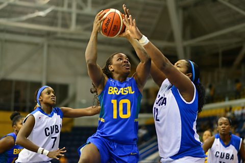 Photo of female basketball player goign for a layup against her opponents