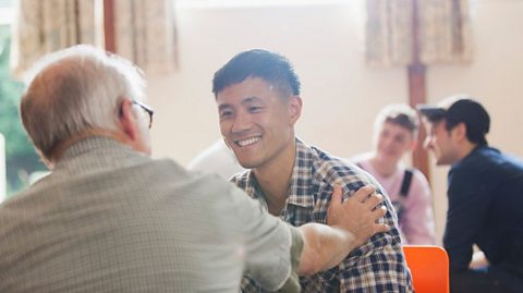 An old man pats the shoulder of a young man.