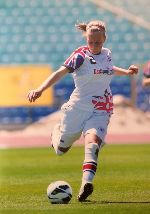 A woman kicking a football.