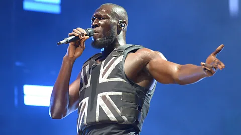 Getty Images Stormzy headlined the 2019 Glastonbury Festival – wearing a stab-proof vest designed by the street artist Banksy (Credit: Getty Images)
