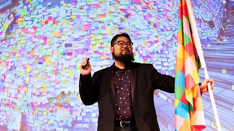 Getty Images Political cartoonist Badiucao holds the flag that was inspired by the Lennon walls around the city (Credit: Getty Images)