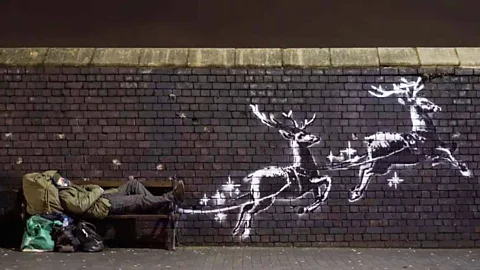 Banksy/Instagram Banksy has just painted reindeer on a wall in Birmingham, pulling a bench that homeless people use as a bed (Credit: Banksy/Instagram)